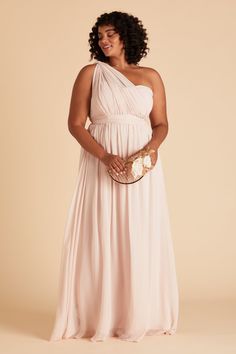 a pregnant woman in a pink gown holding a gold clutch and posing for the camera