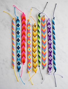 four different colored braids are lined up on a table with string attached to them