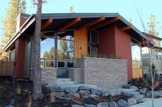 a house that has some rocks in front of it and trees around the outside area