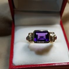 Lovely And Unusual 14kt Yellow Gold Amethyst Ring. High Quality Amethyst Bezel Set Sideways In Between Two Rows Of Channel Set Round Diamonds With A Cabochon Ruby On Either Side. In Excellent Condition, Is About A Size 7 Now, But Sizable. All Stones Are Genuine And 4 Grams In Weight. Elegant Multi-stone Amethyst Ring In Yellow Gold, Fine Jewelry Amethyst Multi-stone, Luxury Purple Multi-stone Sapphire Ring, Formal Purple Sapphire Ring With Gemstone Accents, Purple Ruby Ring For Formal Occasions, Luxury Purple Sapphire Ring For Formal Occasions, Elegant Purple Birthstone Ring With Gemstone Accents, Luxury Purple Multi-stone Rings, Luxury Amethyst Ring Emerald Cut