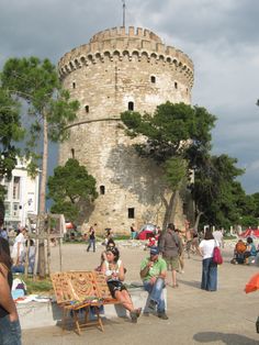 people are sitting on benches in front of an old castle