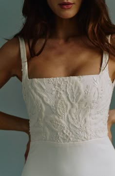 a woman in a white dress with her hands on her hips