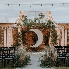 an outdoor ceremony setup with white draping and greenery on the back wall