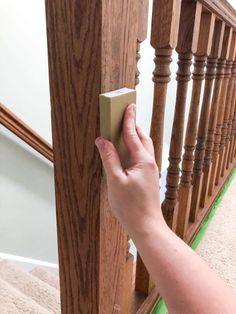 a hand is holding an object near the banister rail on a stair case that has been painted green