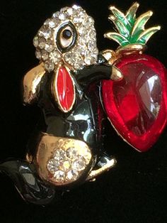 a close up of a brooch with an apple and a bird on it's back