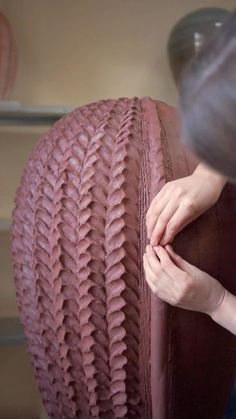 a woman is working on a large piece of furniture with her hands in the fabric