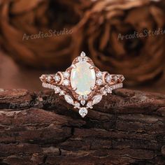 a white opal and diamond ring sitting on top of a piece of wood