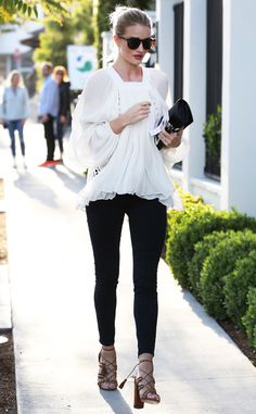 a woman is walking down the sidewalk with her purse