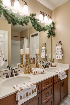 a bathroom decorated for christmas with candles and towels on the sink counter, along with evergreen garland