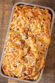 a casserole dish with cheese and other toppings in a pan on a wooden table