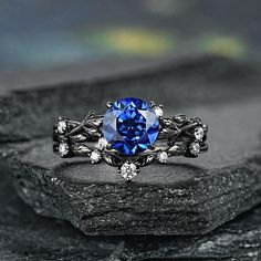 a blue ring sitting on top of a rock next to a black stone slab with white diamonds