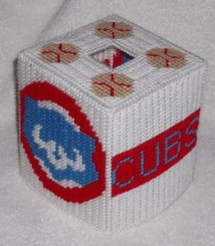 a close up of a knitted dice on a white surface with red and blue letters