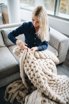 a woman sitting on the floor with a giant knitted blanket