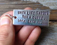 someone is holding a keychain that says, when life throws you a curve lean into it