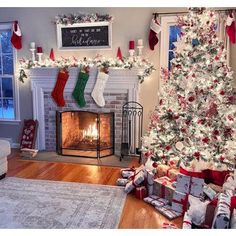 a decorated christmas tree in a living room with stockings on the mantel and fireplace