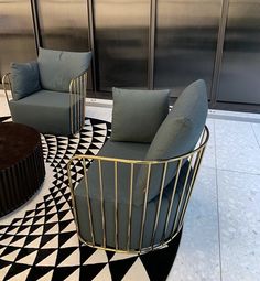 two chairs and a coffee table in a room with black and white floor tiles on the floor