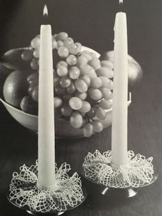 two candles are sitting next to a bowl of fruit