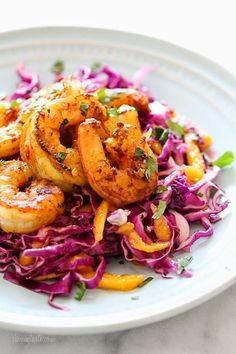 a white plate topped with shrimp, cabbage and coleslaw slaw on top of a table