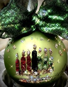 a green ornament with two people on it's side and a bow at the top