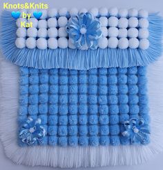 a blue and white wall hanging with pom - poms on the bottom, and two bows at the top