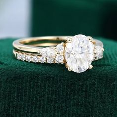 a close up of a ring on top of a green velvet cushion with diamonds around it