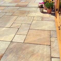 a wooden bench sitting on top of a stone floor next to potted planters