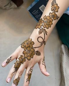 a woman's hand with henna tattoos and flowers on the palm, showing off her