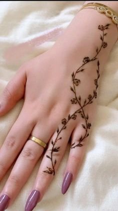 a woman's hand with hennap and flowers on her left hand, sitting on a white blanket