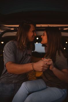 a man and woman sitting in the back of a car together, looking into each other's eyes