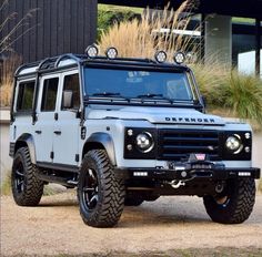 the land rover is parked in front of a building with grass and bushes behind it