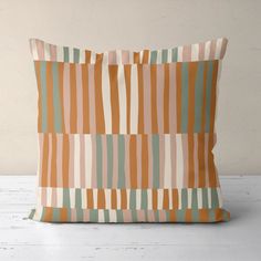 an orange and green striped pillow sitting on top of a white floor next to a wall