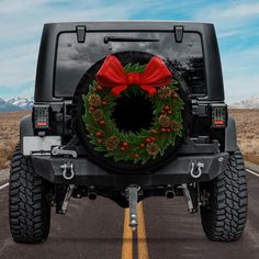 a christmas wreath on the back of a jeep with a red bow and pine cones