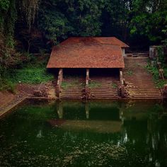 an old wooden cabin sits on the edge of a body of water with steps leading up to it