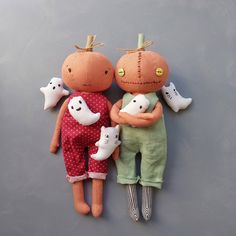 two dolls are laying next to each other on a gray surface, one is holding a cat