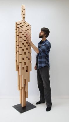 a man standing next to a wooden mannequin made out of wood planks