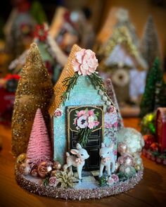 there is a small house made out of fake trees and other decorations on the table