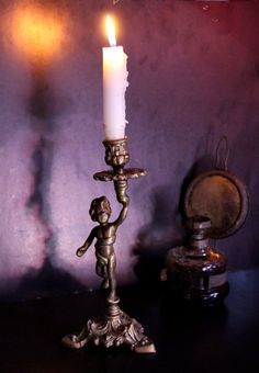 a candle that is sitting on top of a table next to an old fashioned clock