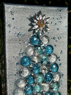 a small christmas tree made out of glass beads and silver balls with a sunburst on top