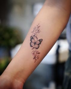 a woman's arm with a butterfly and flowers tattoo on the left side of her arm