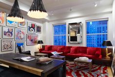 a living room filled with red couches and pictures on the wall above it's coffee table