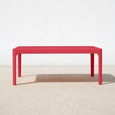 a red table sitting in front of a white wall