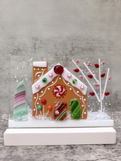 a gingerbread house with candy and candies in the front, on a white stand