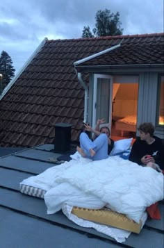 two people sitting on the roof of a house