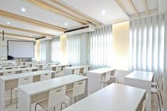 an empty classroom with white desks and chairs