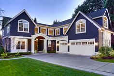 a blue house with white trim and two car garages on the front, surrounded by lush green grass