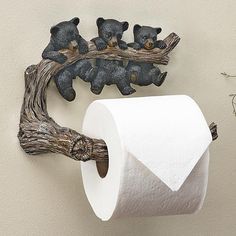 three teddy bears are sitting on a branch next to a roll of toilet paper that is hanging from the wall