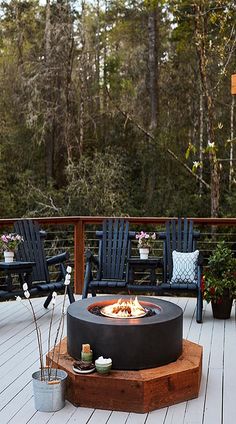 a fire pit sitting on top of a wooden deck next to two blue adiron chairs