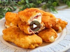 some fried food on a white plate with green plants in the background and a video player