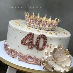 a white cake with gold decorations and a tiara on top that reads forty birthday