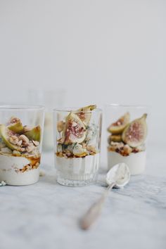 three glasses filled with food sitting on top of a table next to spoons and utensils